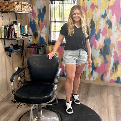 Lexi Vaughn, owner and operator of Salon Lex, stands beside a barber chair in her salon