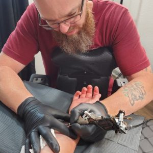 Hogshead Tattoo owner starting a tattoo on customer's wrist area