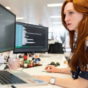 Young professional sitting at desk with multiple computer monitors